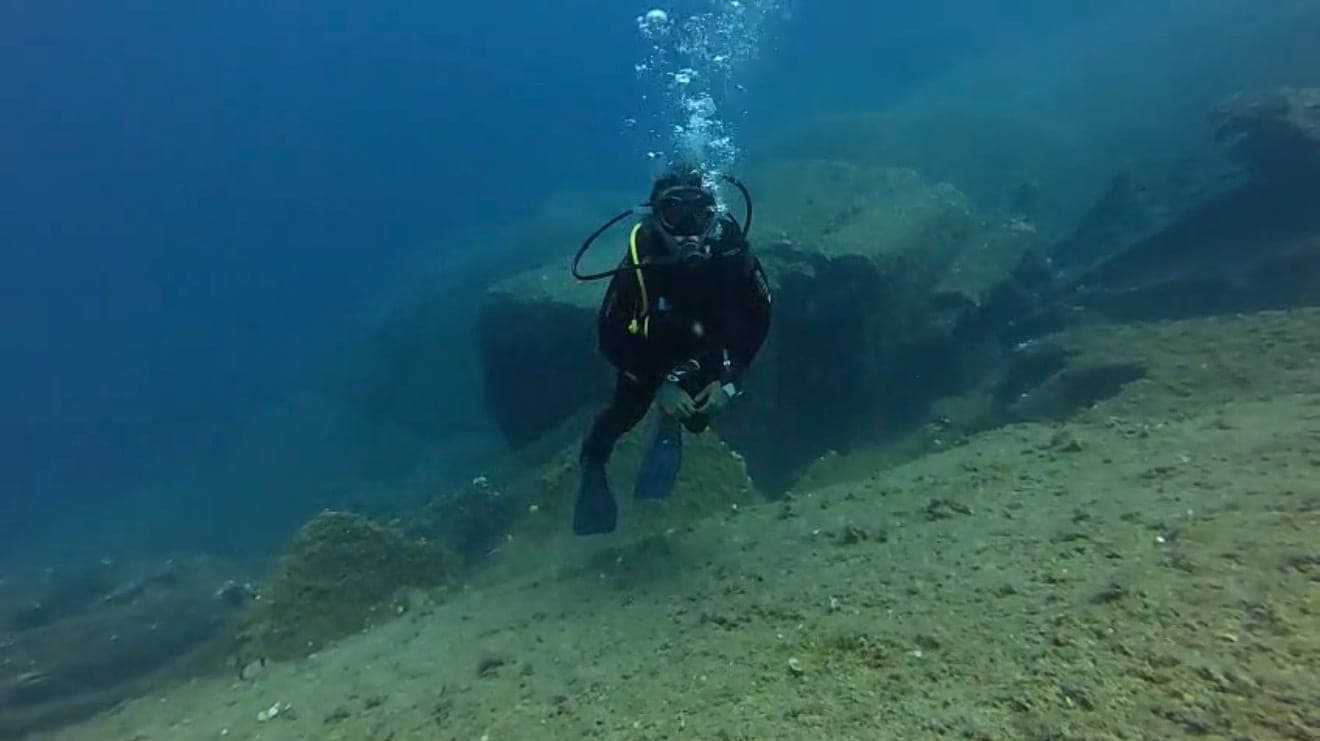 Diver moving steadily along the seabed in open water